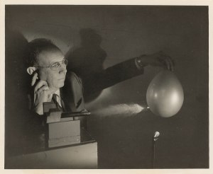 1959 original stroboscopic photo of famed M.I.T. engineer and photography pioneer Harold Edgerton.  The ultra high speed photo shows Edgerton holding a balloon as a bullet is shot through it.  The back has a press release tag from M.I.T.